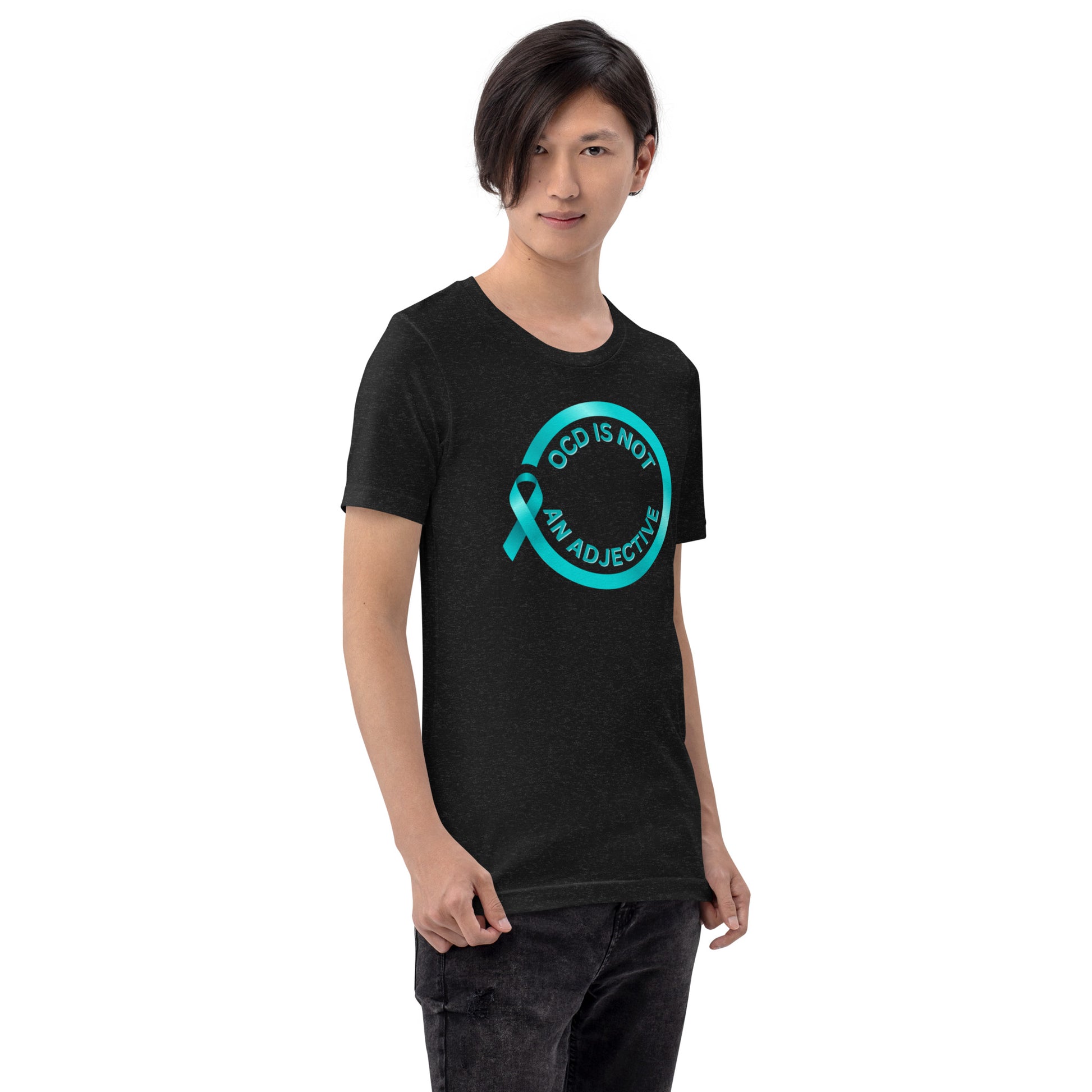 A person with straight dark hair wears NeuroNiche Design’s "OCD Is Not An Adjective" black t-shirt, made from soft combed cotton, featuring a teal awareness ribbon and blue text. They stand facing the camera.