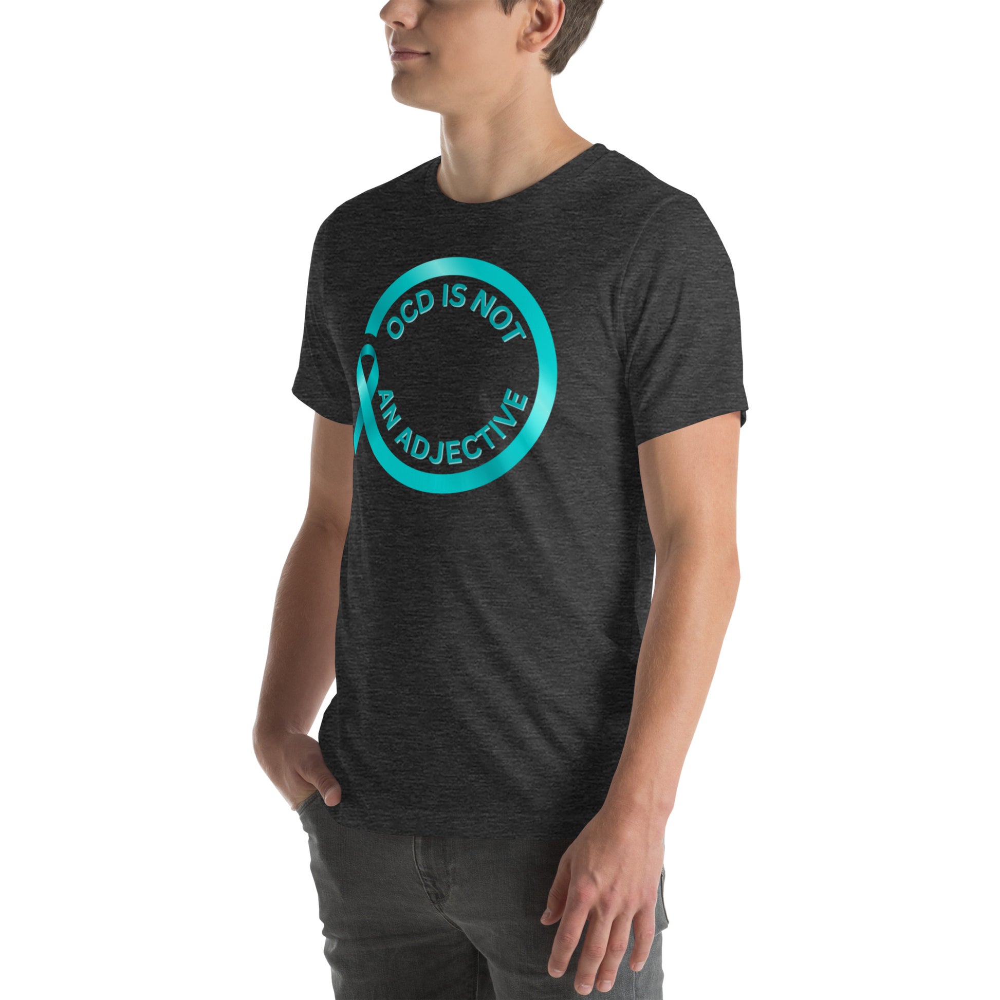 A person wears the NeuroNiche Design "OCD Is Not An Adjective" t-shirt—a dark gray, combed cotton shirt featuring a turquoise circle and ribbon graphic and the bold statement across the front.